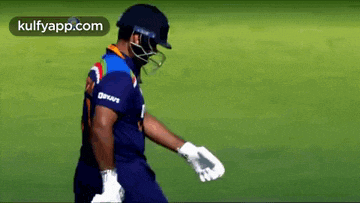 a man wearing a helmet and gloves is walking on a field .