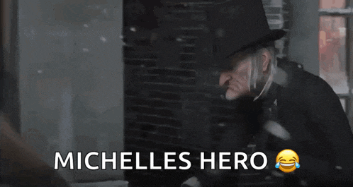 a man in a top hat is standing in front of a window with the words michelles hero below him