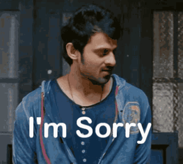 a man in a blue shirt says i 'm sorry in front of a door