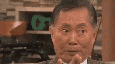a man in a suit and tie is making a funny face while sitting at a table .
