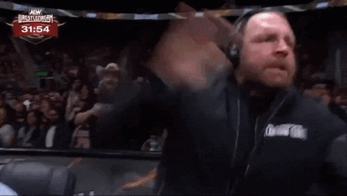 a man in a cowboy hat is talking into a microphone in front of a crowd at a wrestling event