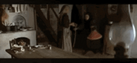 two women are standing next to each other in a room in front of a fireplace .