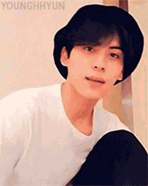 a young man wearing a hat and a white t-shirt is sitting down .