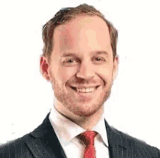a man in a suit and tie is smiling for the camera on a white background .