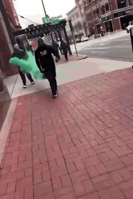 a person walking down a brick sidewalk with a green balloon in their hand and a sign that says one way