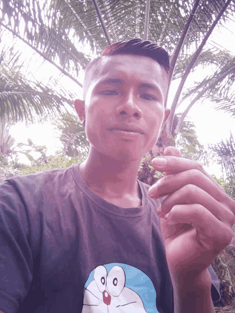 a man wearing a doraemon shirt holds a cigarette in his hand