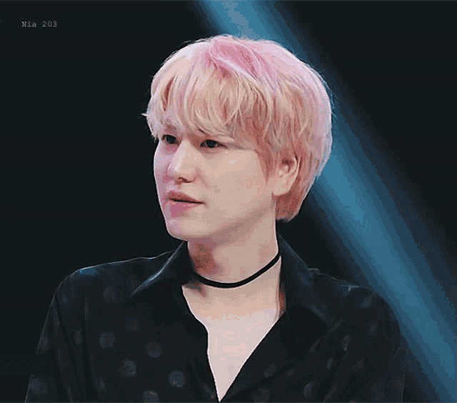 a young man with pink hair is wearing a black shirt and a choker