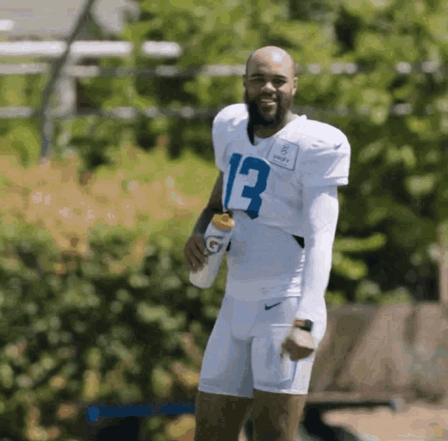 a football player with the number 13 on his jersey holds a gatorade bottle