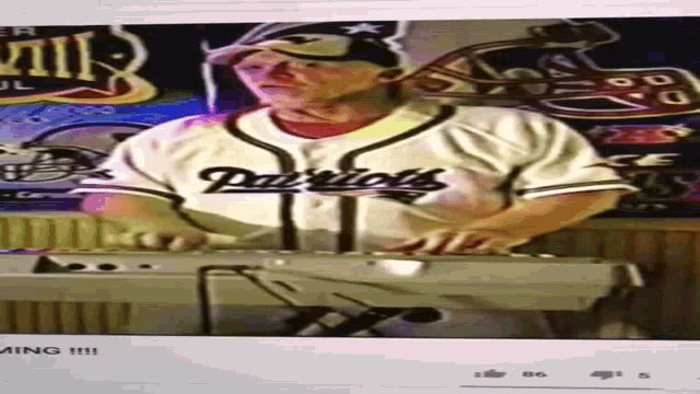 a man in a patriots jersey is standing in front of a keyboard