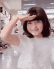 a young girl is holding her hand to her forehead while smiling .