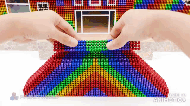 a person is playing with a house made out of magnet balls