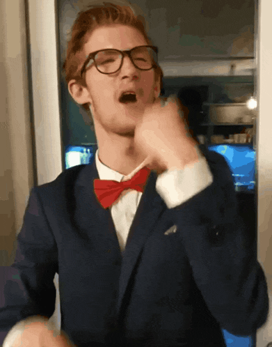 a man wearing glasses and a red bow tie is singing