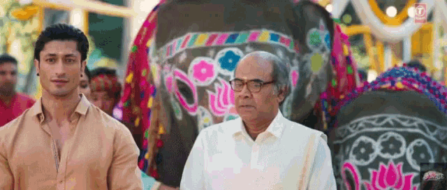 a man and an older man are standing in front of an elephant
