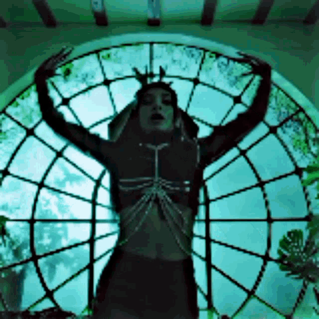 a woman stands in front of a stained glass window with her arms outstretched