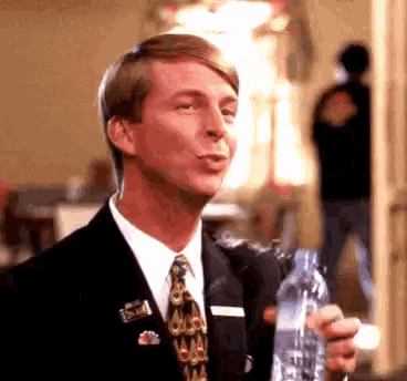 a man in a suit and tie holds a bottle of water