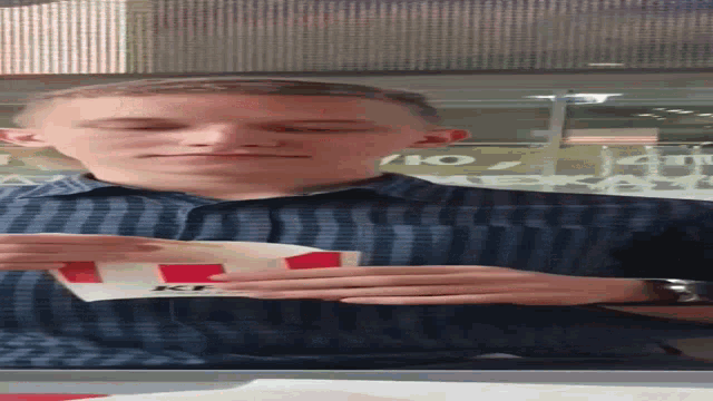 a man in a blue plaid shirt is holding a kfc bag