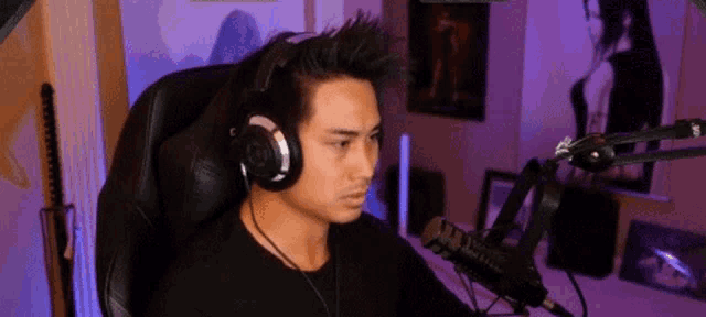 a man wearing headphones is sitting in a chair in front of a microphone in a room .