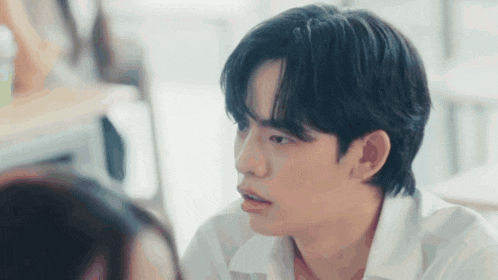 a young man in a white shirt is looking at a girl .