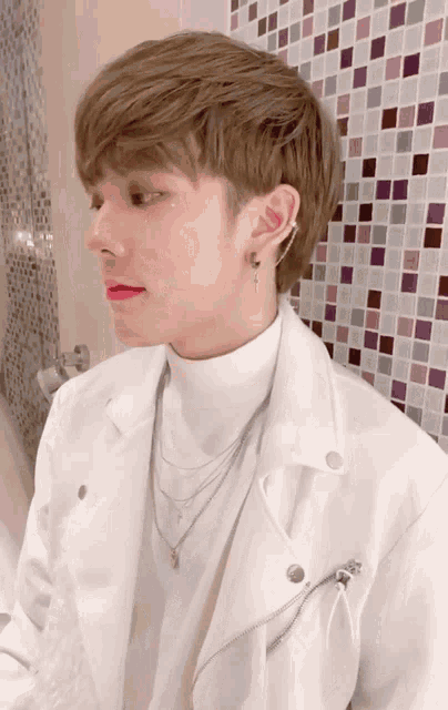 a young man wearing a white jacket and a necklace