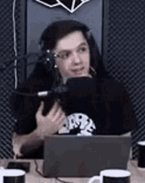 a man wearing headphones is sitting at a table with a laptop computer .