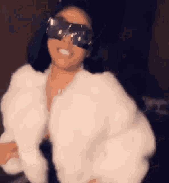a woman wearing a fur coat and sunglasses is dancing .