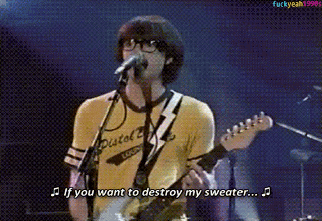 a man singing into a microphone and playing a guitar with the words if you want to destroy my sweater