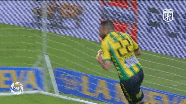 a man in a yellow and green jersey holds a soccer ball in his hand