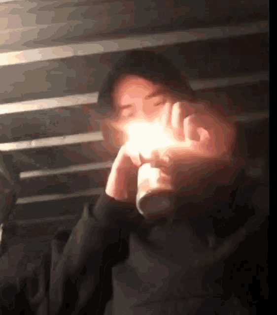 a person is lighting a candle in a dark room with a candle in their hand .