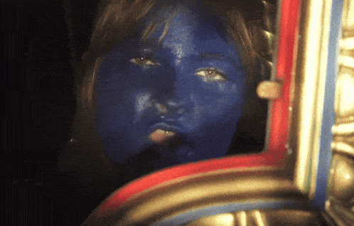 a woman with blue paint on her face looks at herself in the mirror