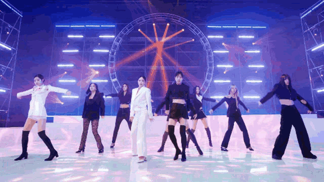 a group of women are dancing in front of a large ferris wheel