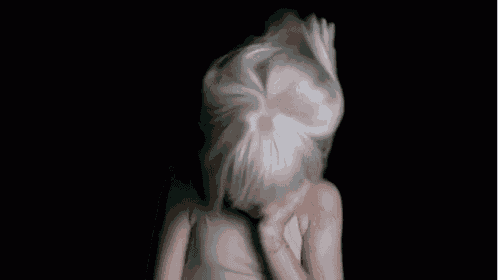a woman wearing a white wig is covering her face with her hands .