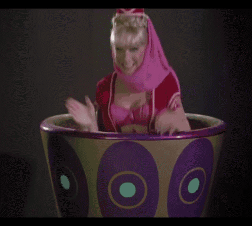 a woman in a pink and purple costume is sitting in a purple and green bowl