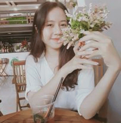 a woman is sitting at a table holding a bouquet of flowers and drinking a drink .