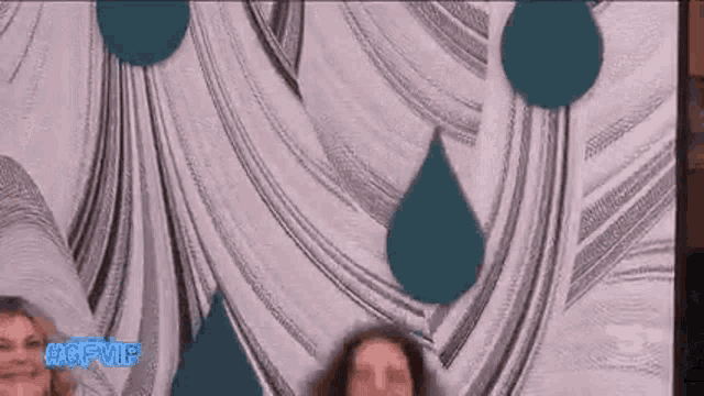 a group of people are standing in front of a wall with a painting of drops of water .