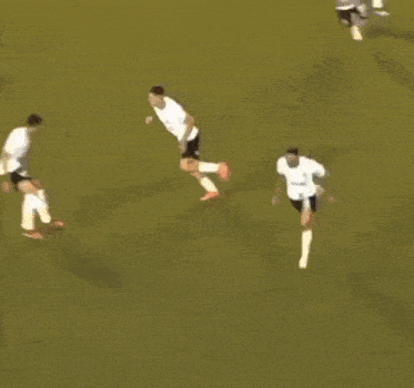 a soccer player in a white shirt and black shorts is jumping in the air on a field .