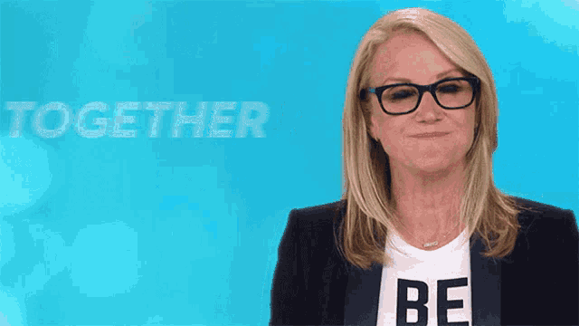 a woman wearing glasses and a shirt that says be