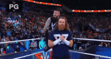 two men are standing in a wrestling ring .
