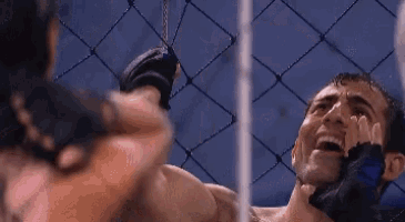 a man is crying in a boxing ring while another man is hitting him with a punch .