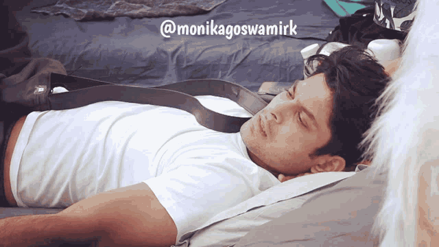a man laying on a bed with a belt around his neck and the name monikagoswamirk on the bottom right