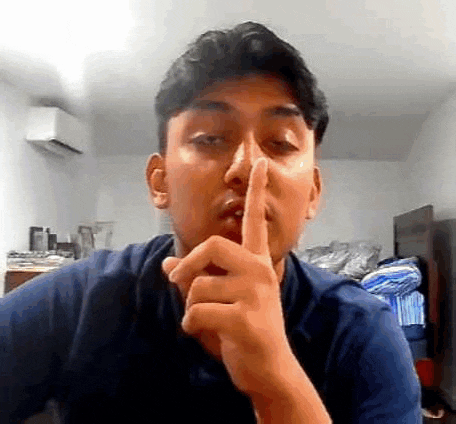 a man is making a shhh gesture with his finger to his mouth .