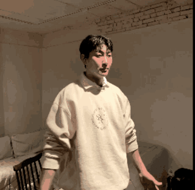a man wearing a white sweater with a circle on the front