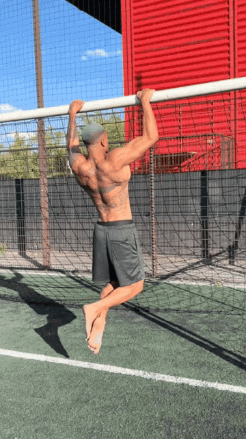 a shirtless man is doing a pull up on a soccer field