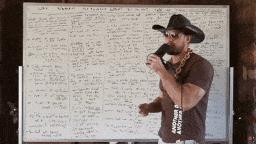 a man wearing a cowboy hat and sunglasses stands in front of a white board that says " why women "