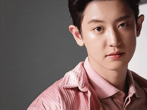a close up of a young man 's face with a pink shirt on