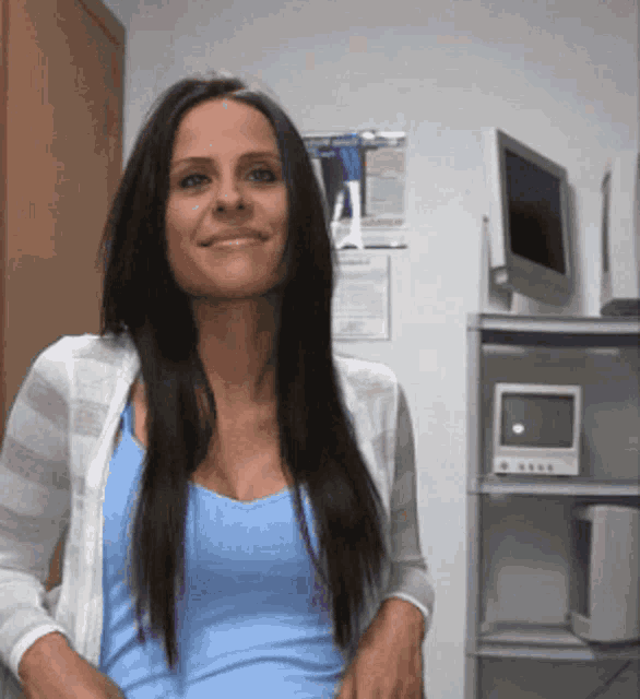 a woman in a blue tank top is smiling in front of a computer monitor
