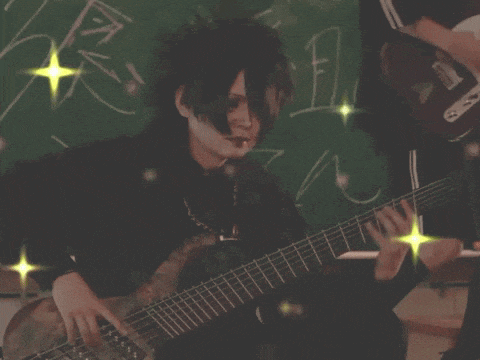 a person playing a guitar in front of a blackboard with chinese writing