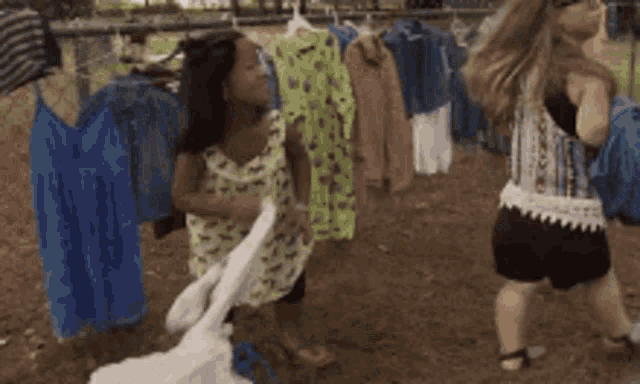 two girls playing with clothes hanging on a clothes line