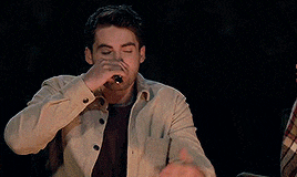 a man in a tan jacket is holding an oreo ice cream sandwich in his hand .