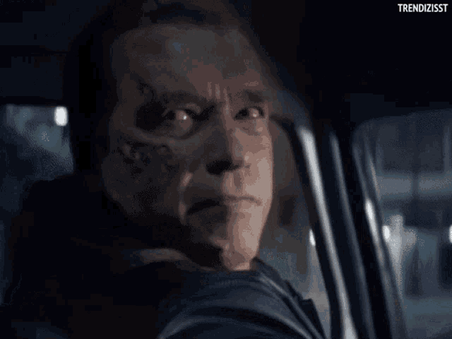 arnold schwarzenegger is making a funny face while sitting in a car .