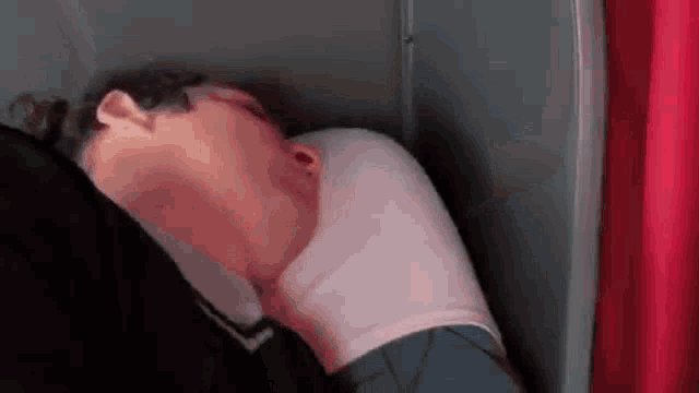 a man is sleeping on a pillow in a closet .